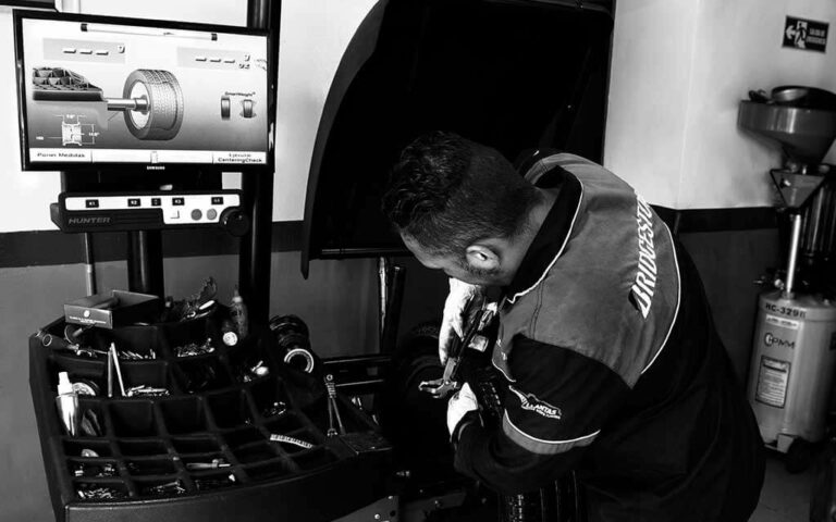 Hombre realizando balanceo de vehículo en máquina con computador